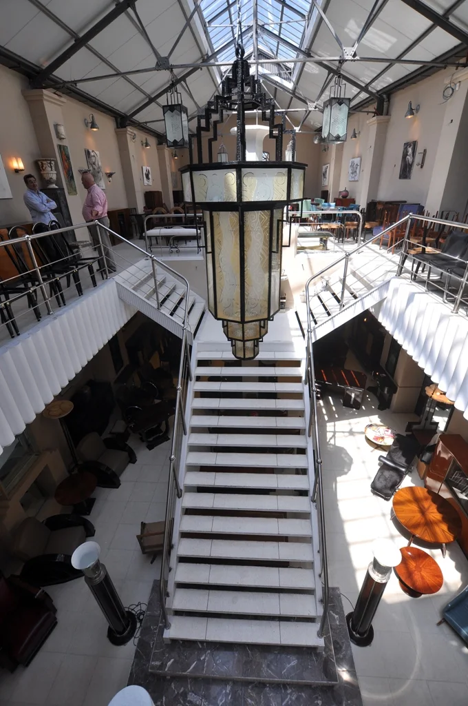 Vista interior del local Luxury Design Store con escaleras y decoración antigua.