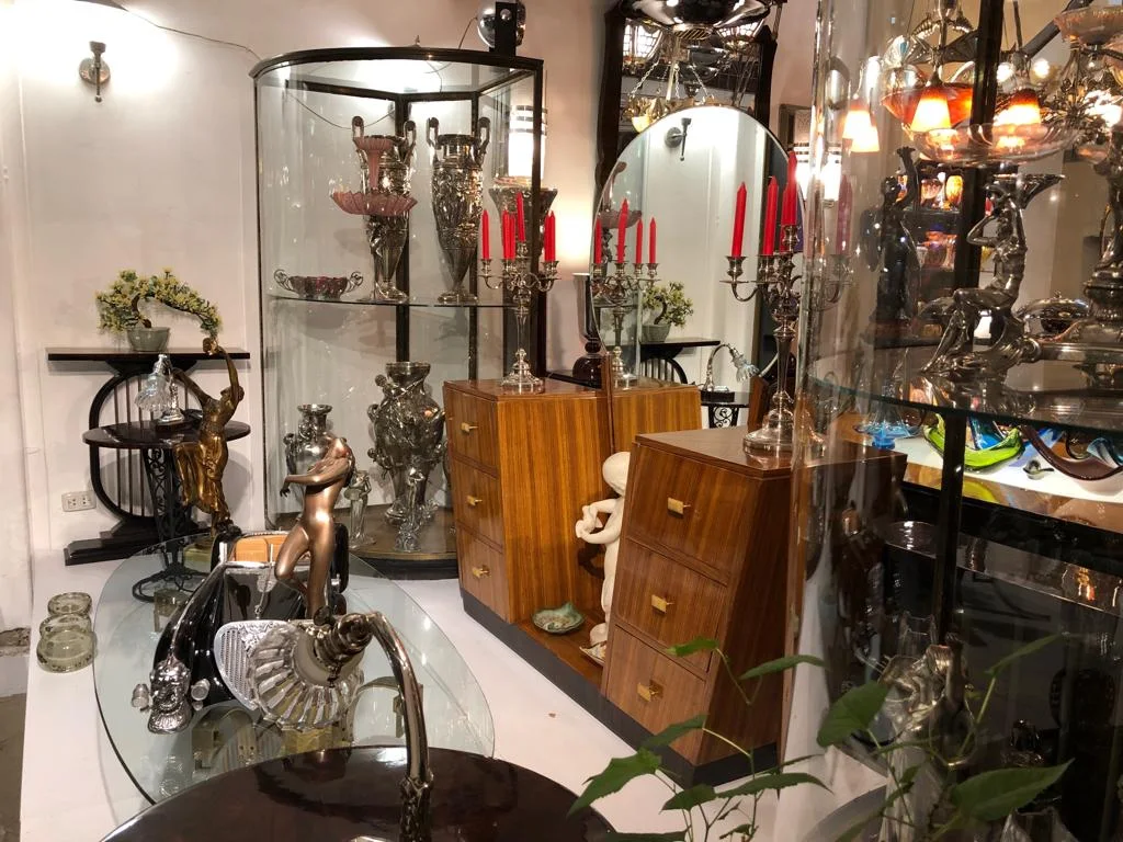 Vitrine con antigüedades varios objetos decorativos y candelabros rojos en Luxury Design Store