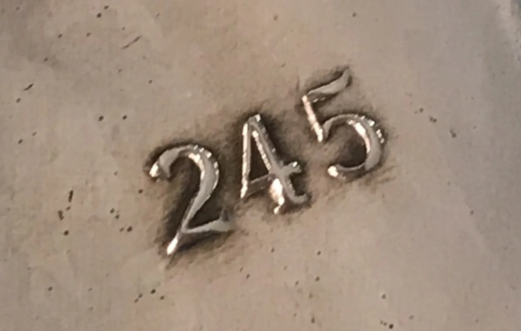 Detail of serial number 245 on an antique item.