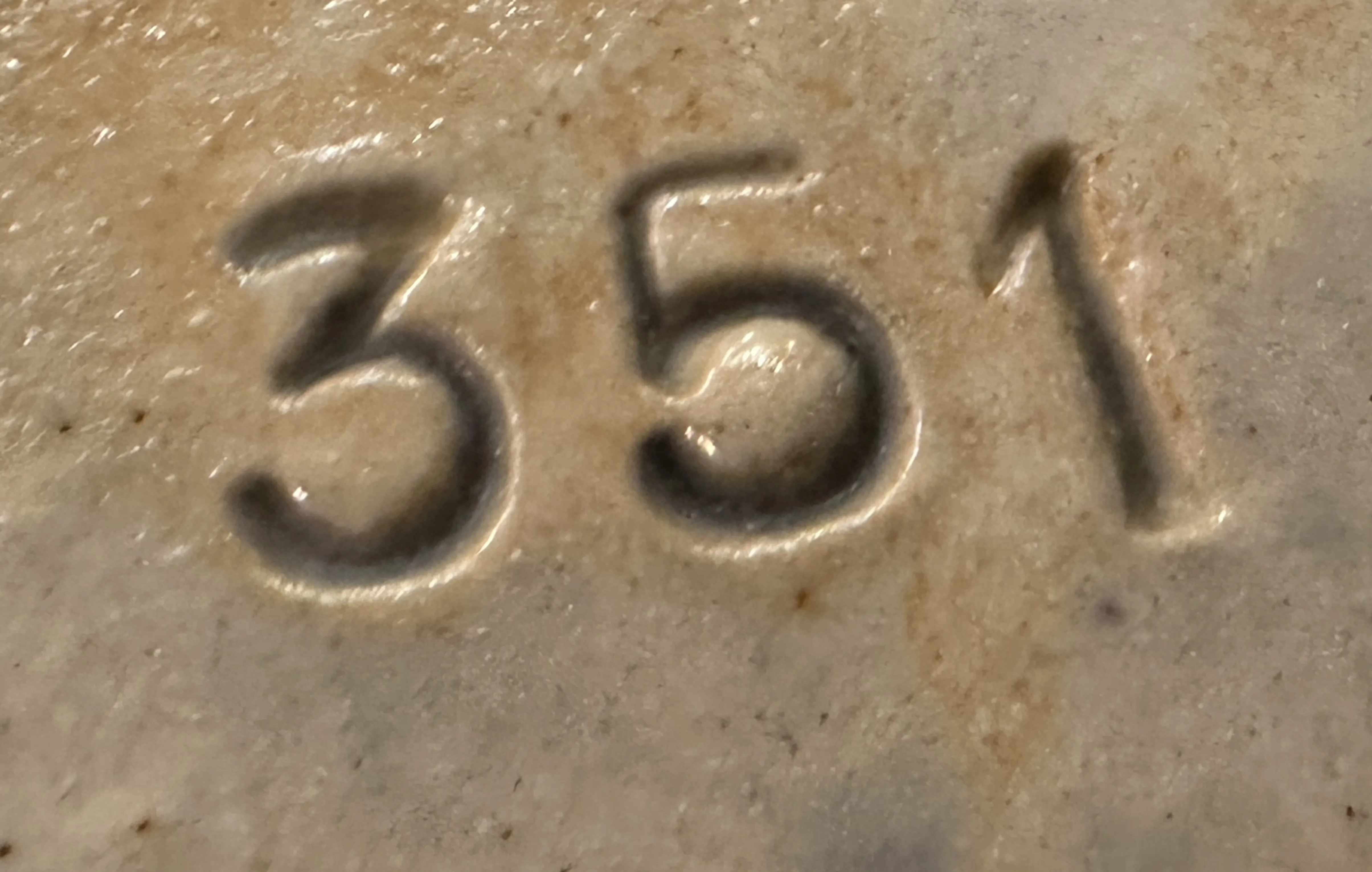 Primo piano di un numero di serie 351 su un'antiquità, inciso.