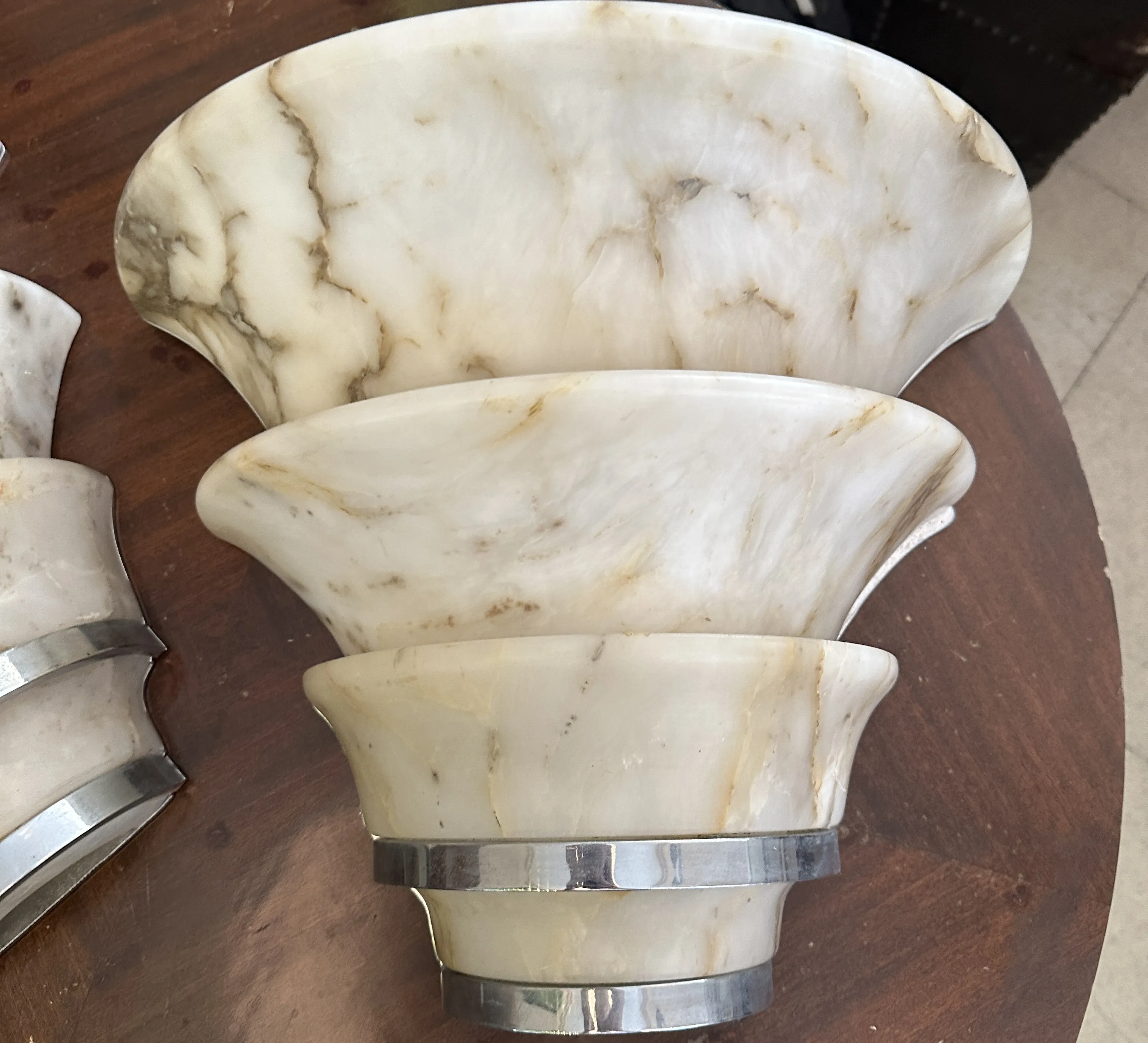 Antique pair of sconces with a light-colored curved design, on a wooden table