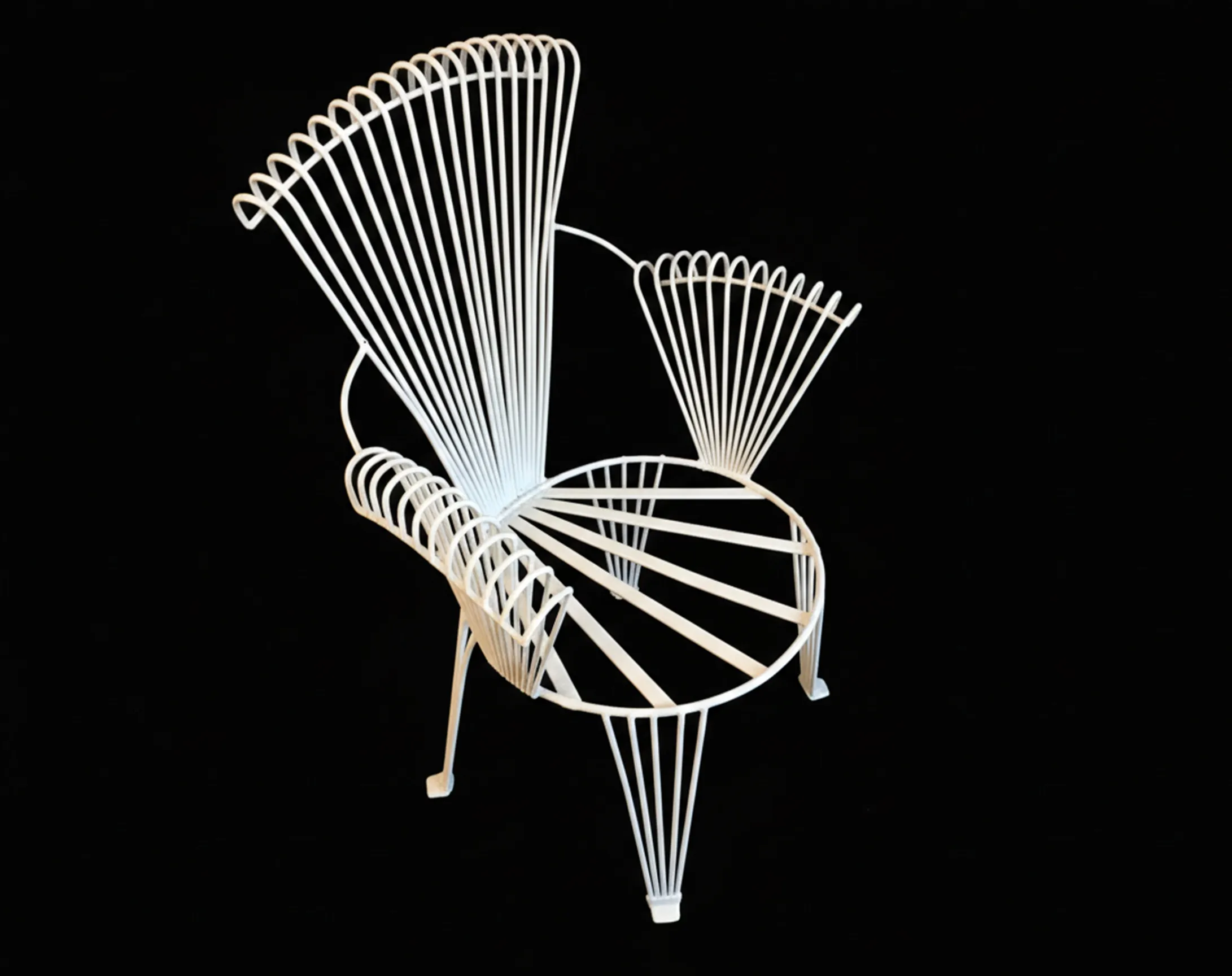 Four antique garden armchairs with elegant lines on a dark background.