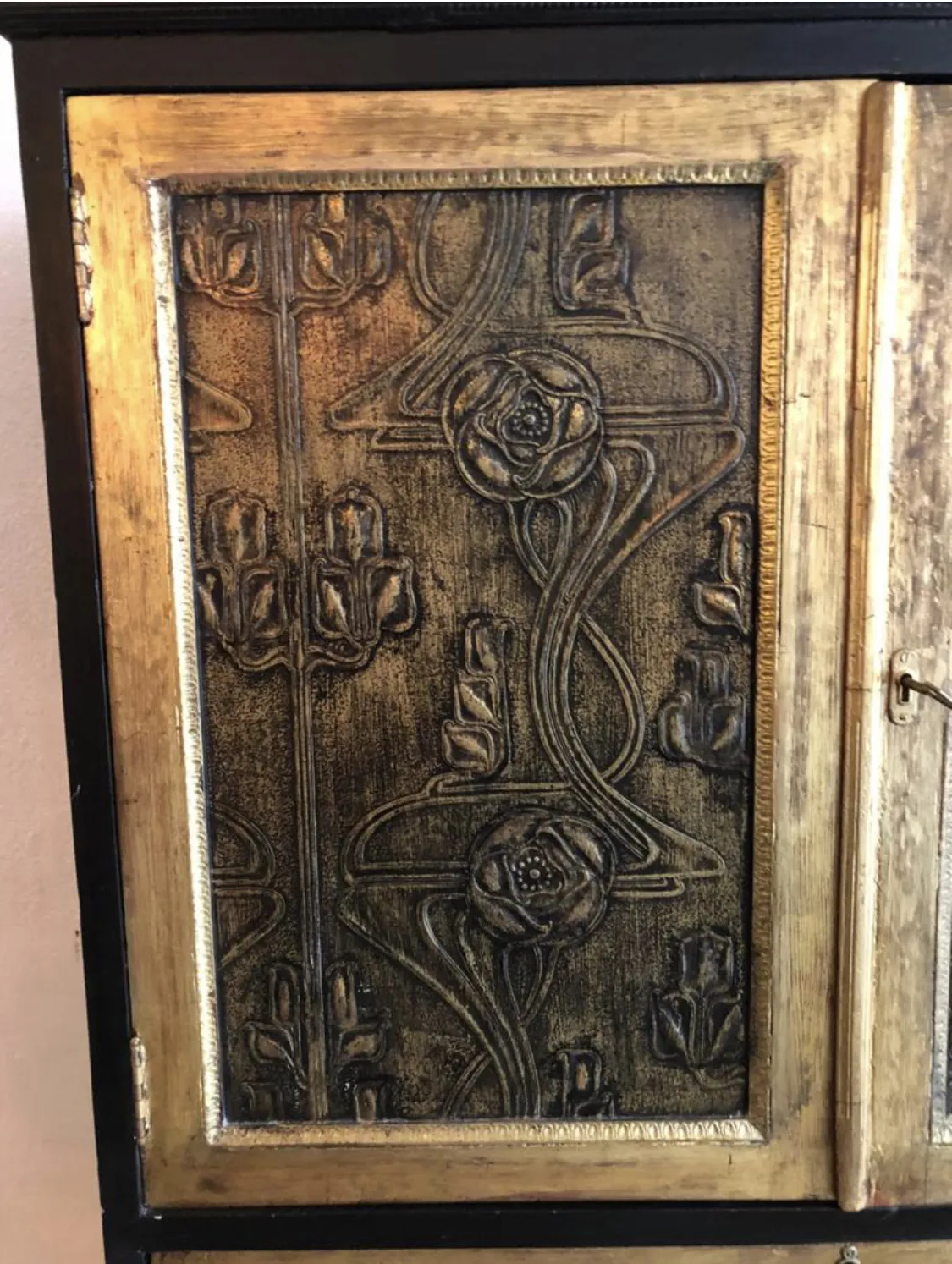 Antique bar cabinet featuring embossed floral design in gold and black.
