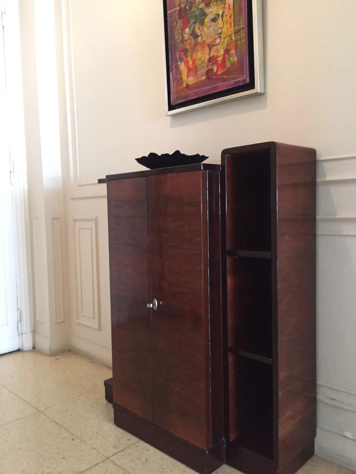 Antique bookcase featuring elegant design and visible shelves, accompanied by a piece of art