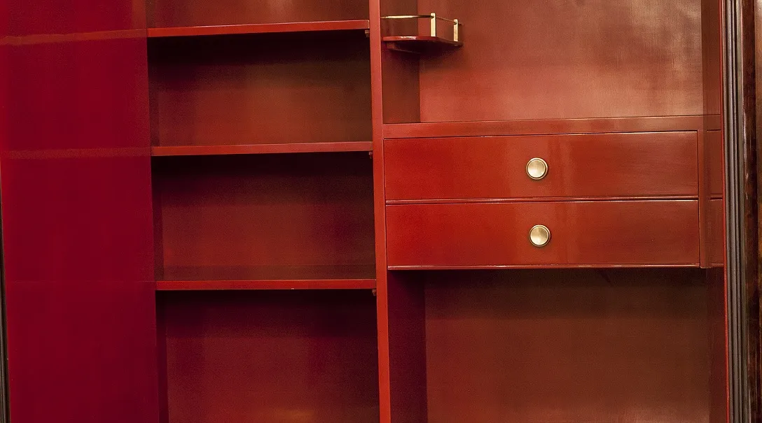 Antique bookcase with shelves and two golden drawers in a soft environment.
