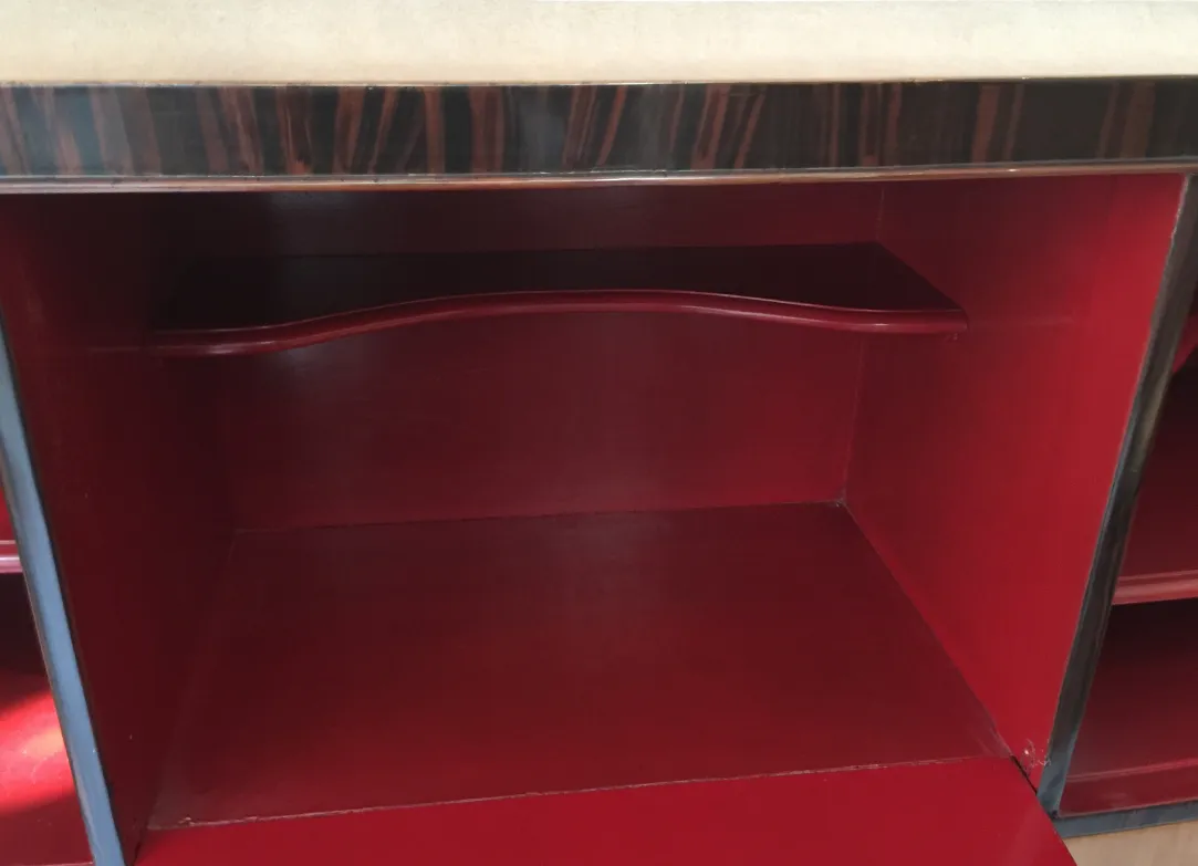 Interior view of an antique bookcase with red shelves and elegant finishes