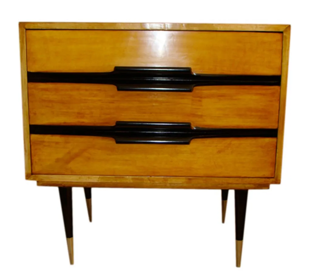 Antique bedside table with two drawers and black legs, in a cozy setting.