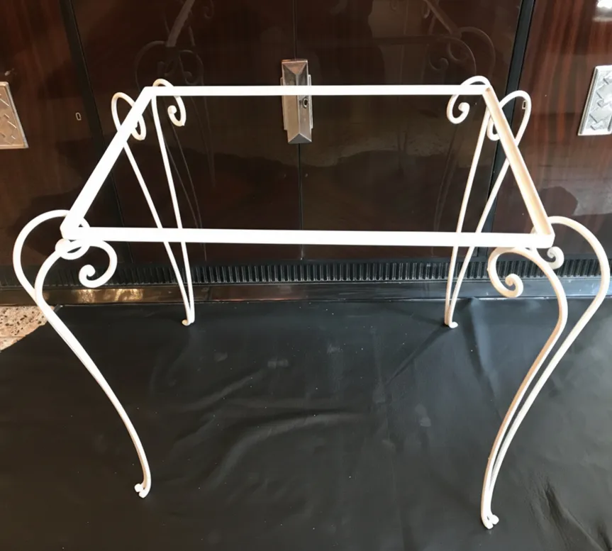 antique garden table with decorative details on legs against a black background