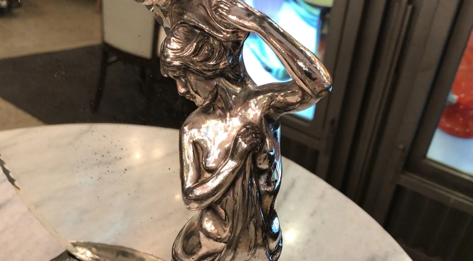 antique mirror with decorative base and female figure, reflection on marble