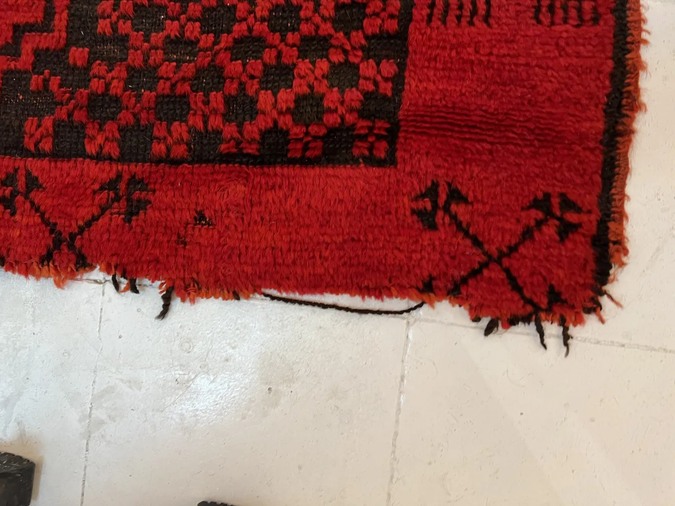 tappeto antico rosso con figure decorative sui bordi