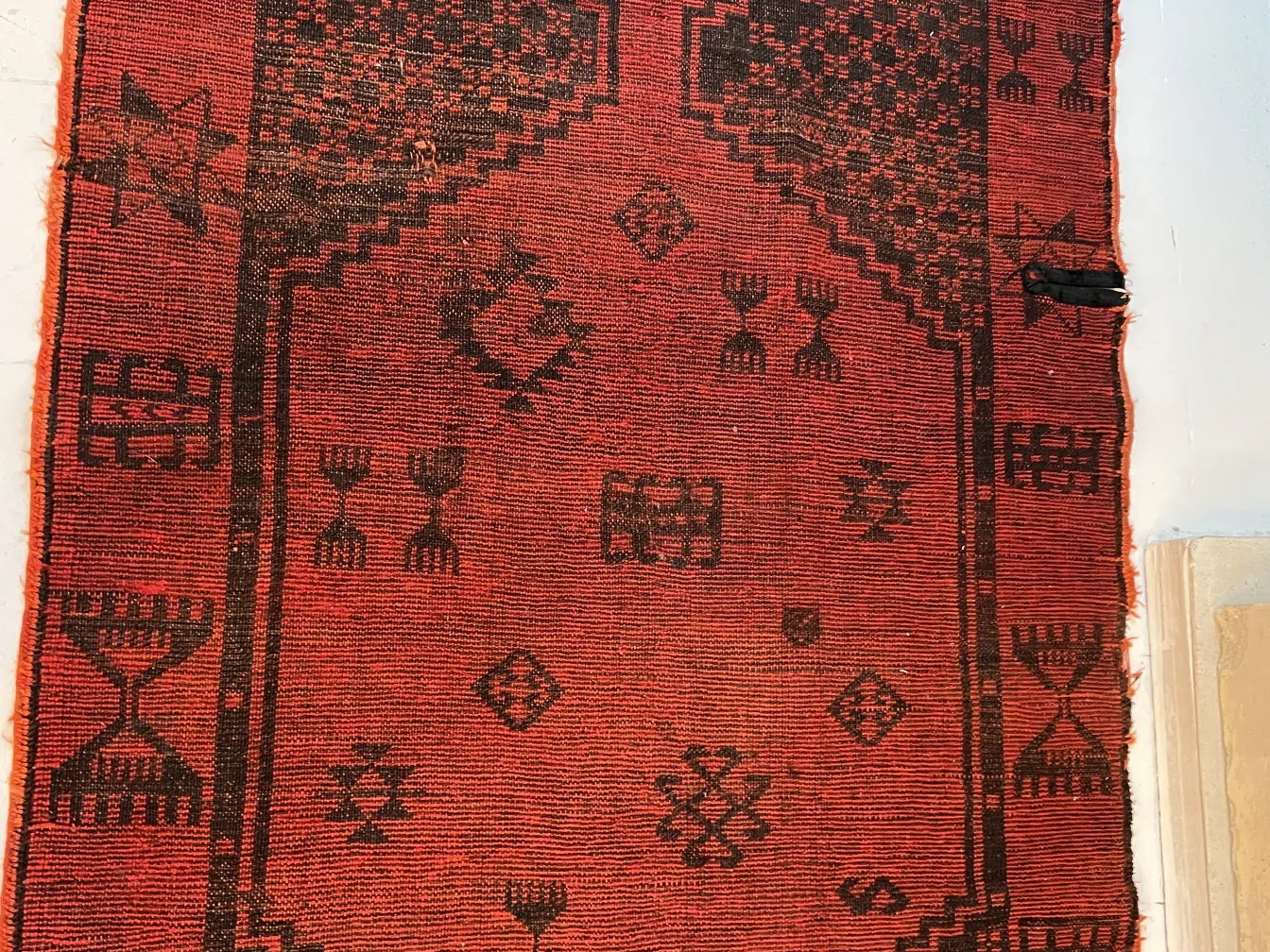 Tappeto rosso antico con motivi decorativi neri.