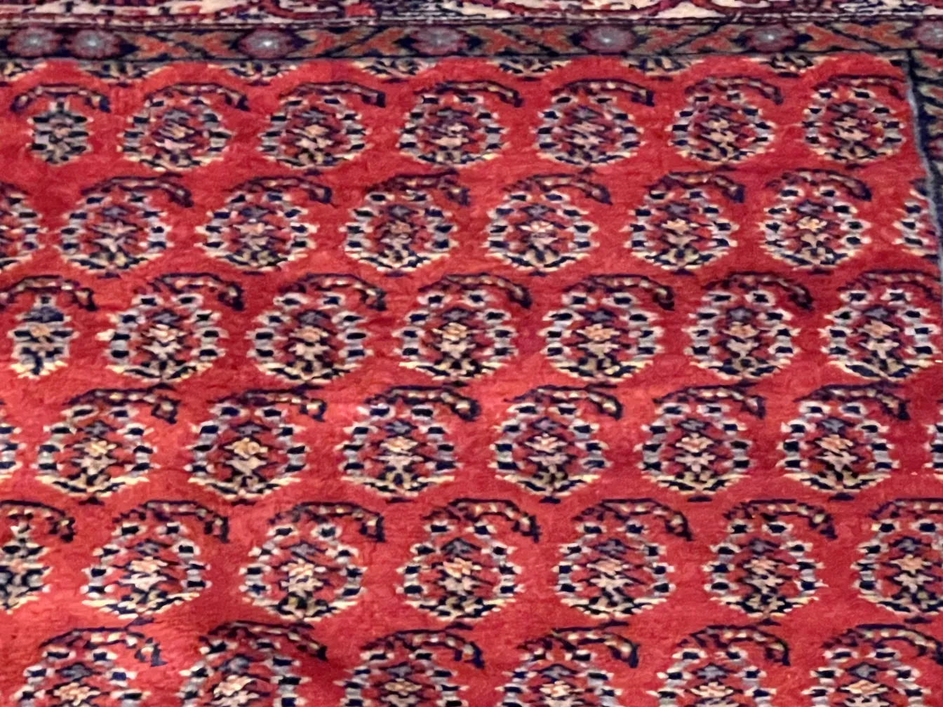 tappeto antico rosso con motivi intricati in un ambiente accogliente