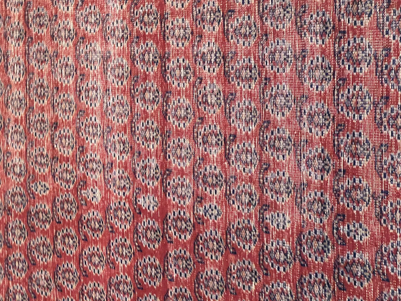 tappeto antico con motivi geometrici in rosso e blu