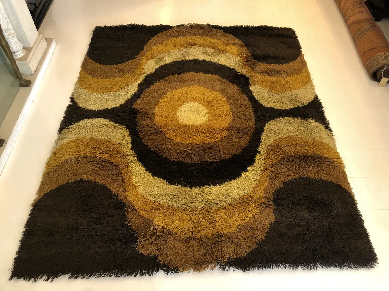 Tappeto antico con motivi geometrici in tonalità di marrone e beige, in un ambiente accogliente.
