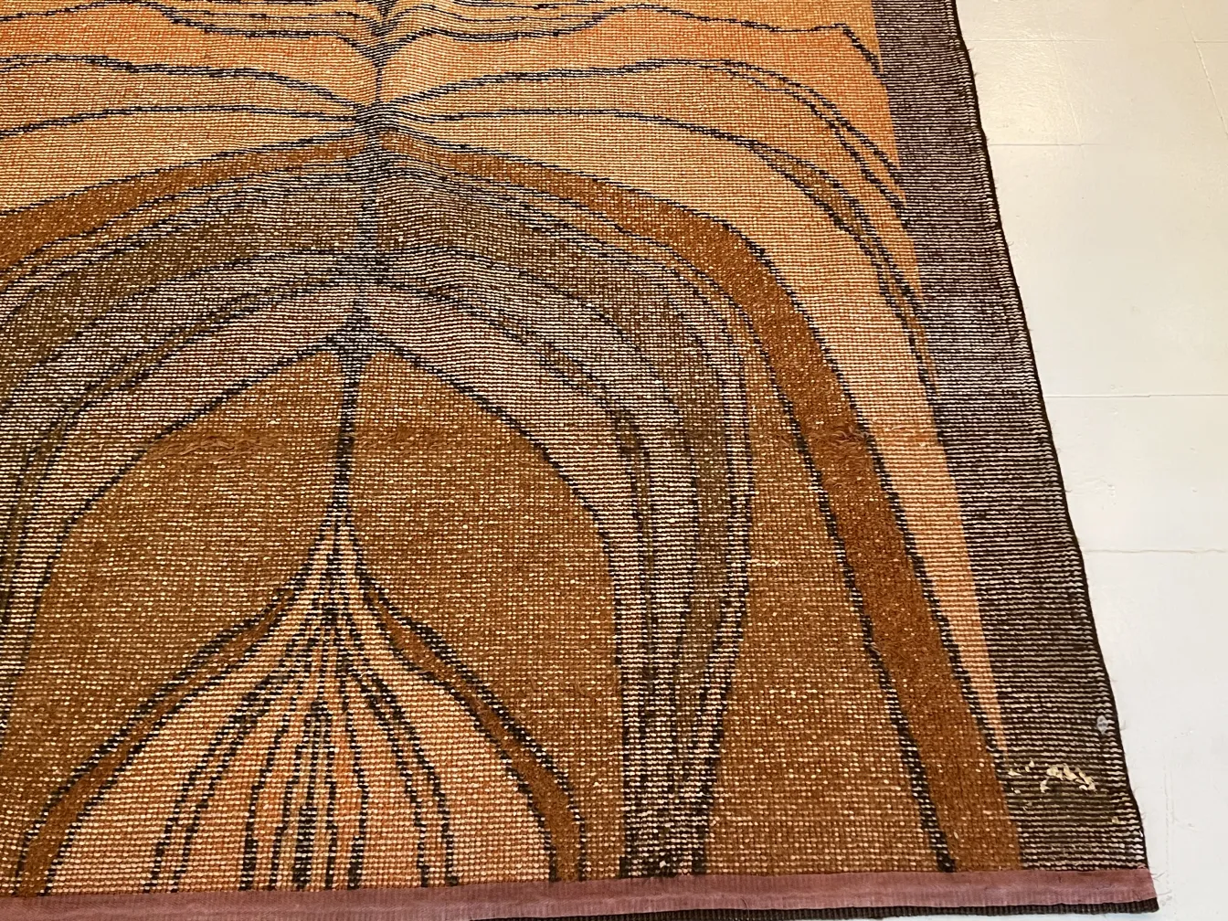 Tappeto antico con un design astratto in tonalità calde, in un ambiente elegante