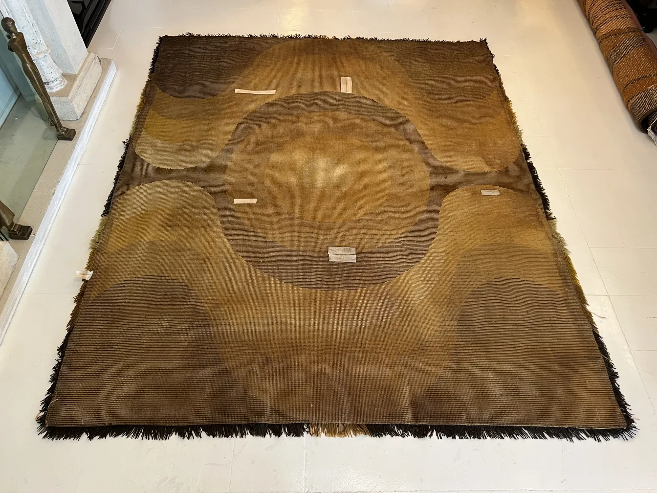 tappeto antico con design geometrico in tonalità marroni, arricchisce uno spazio elegante.