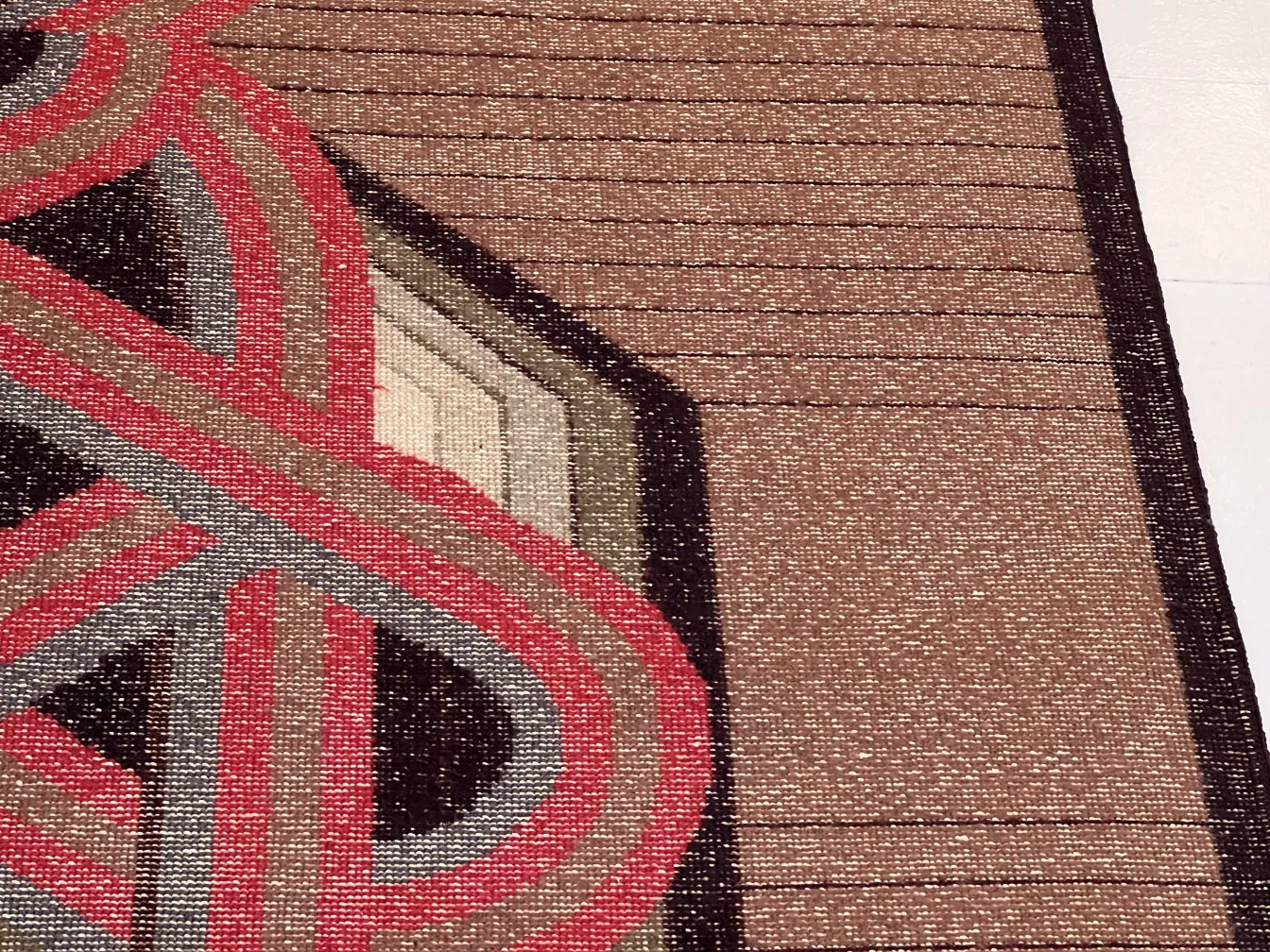 Tappeto antico con tonalità terrose e forme geometriche.