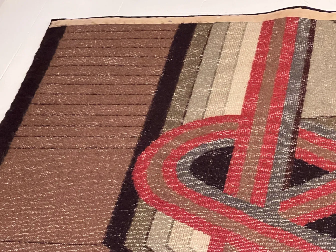 tappeto antico con motivi geometrici in marrone e rosso, in un ambiente elegante