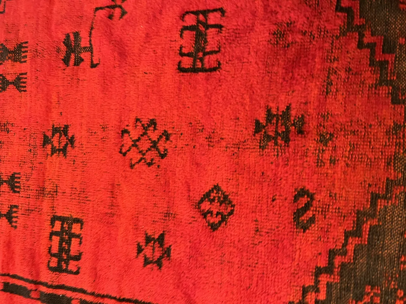 tappeto antico rosso con motivi decorativi neri