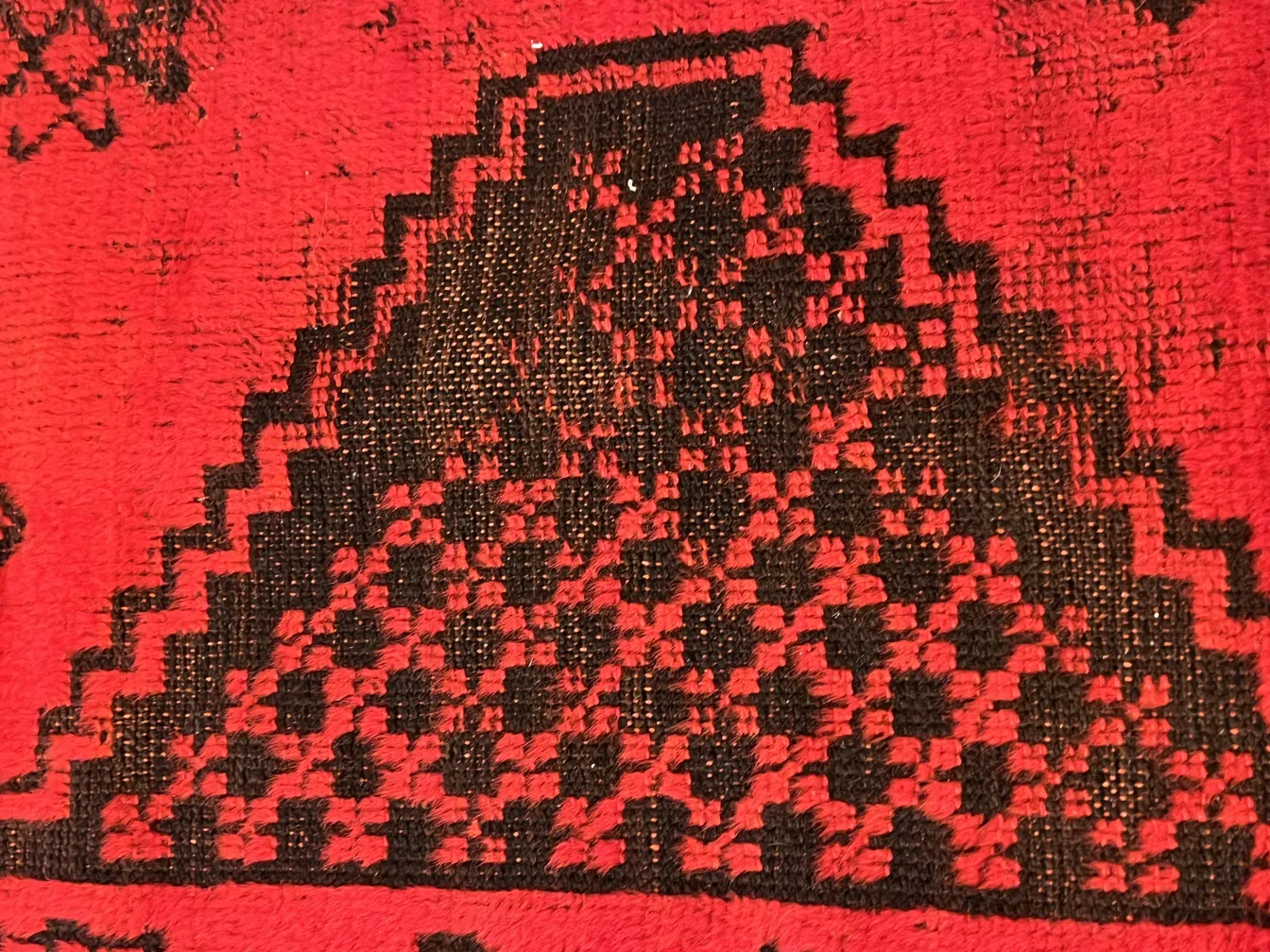 tappeto antico rosso con motivi neri e dettagli geometrici