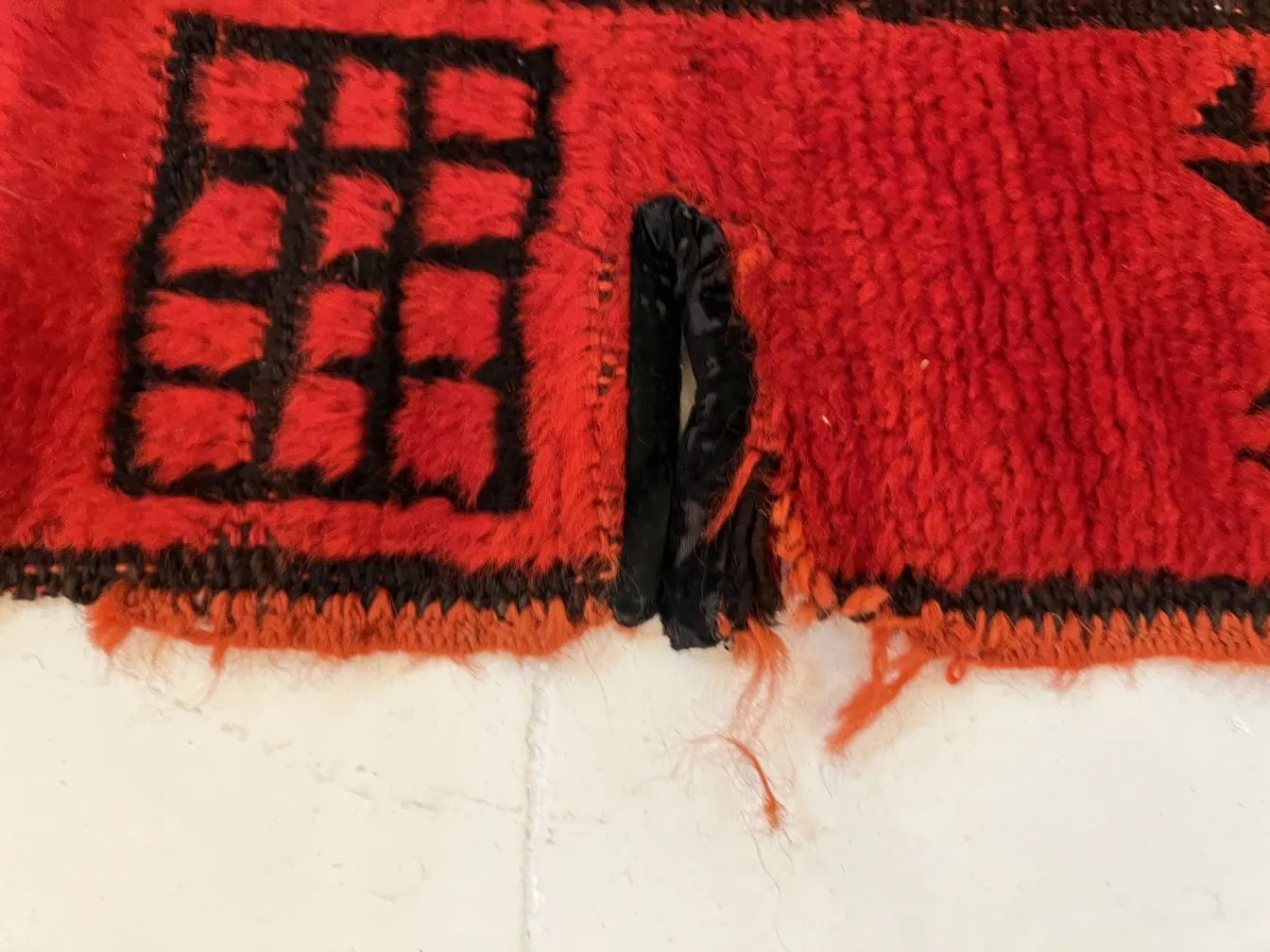 tappeto antico rosso con design geometrico, mostra segni di usura