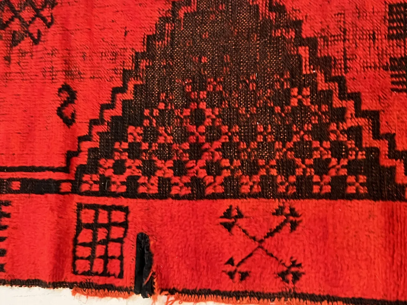 tappeto antico rosso con motivi geometrici e dettagli