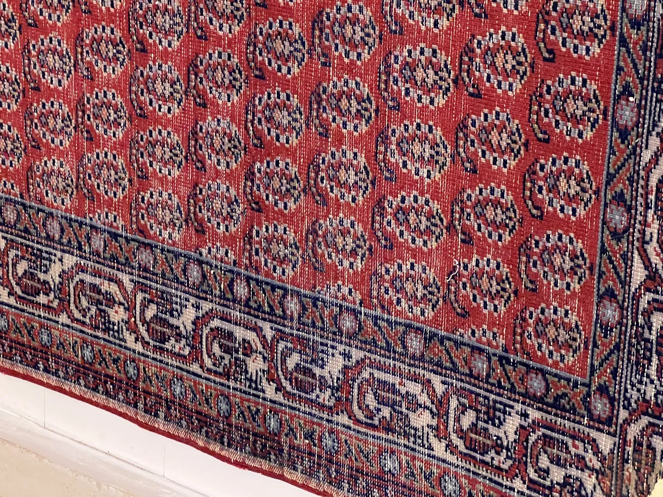 tappeto antico con motivi intricati in tonalità rosse e blu, decorando una stanza