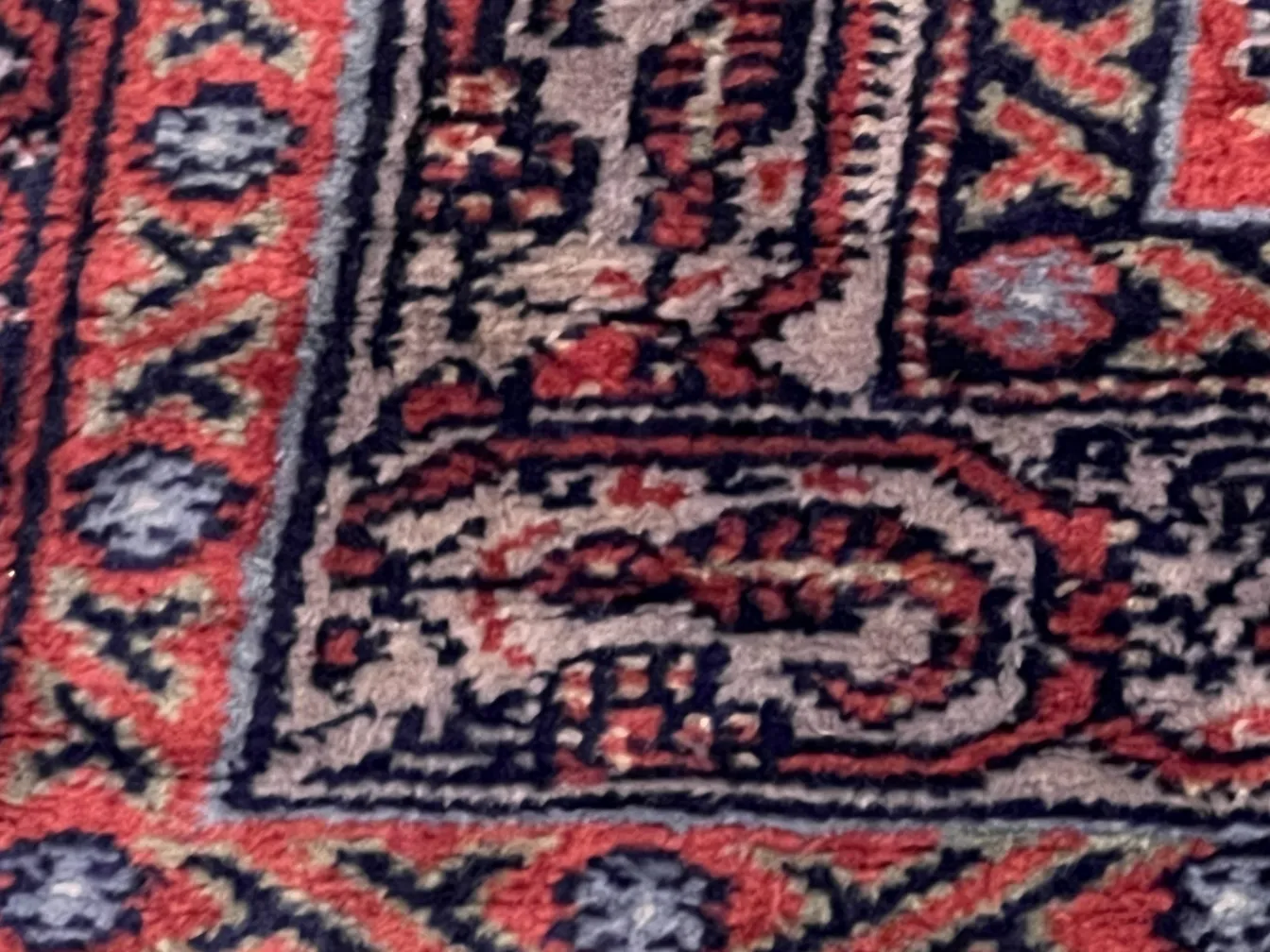 tappeto antico con motivi intricati in tonalità di rosso e blu