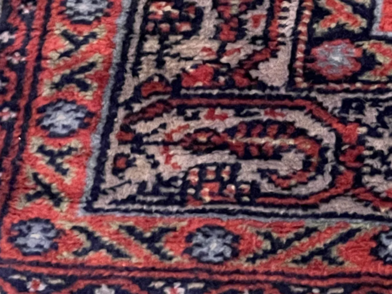 Tappeto antico con colori ricchi e motivi tradizionali in un ambiente classico.