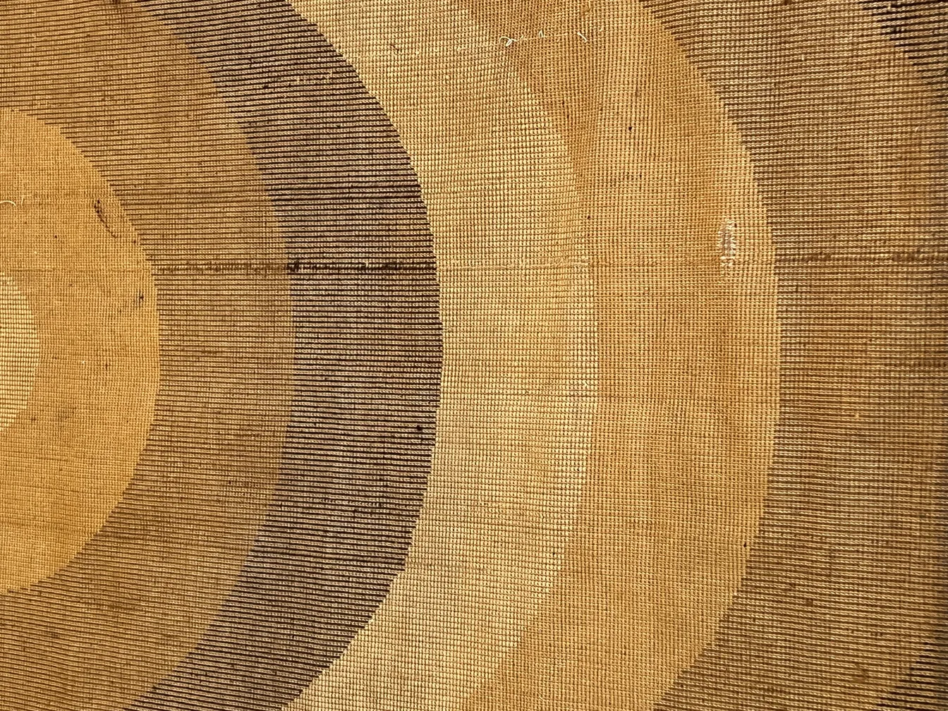 Tappeto antico con motivi circolari in toni caldi, texture rustiche, ideale per la decorazione.
