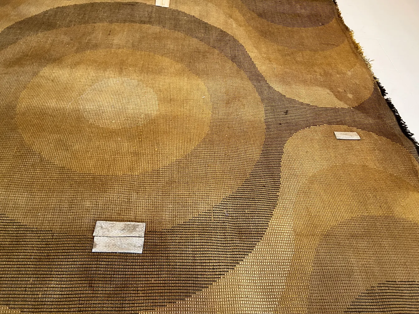 tappeto antico con disegni circolari marroni e gialli, dettaglio visibile