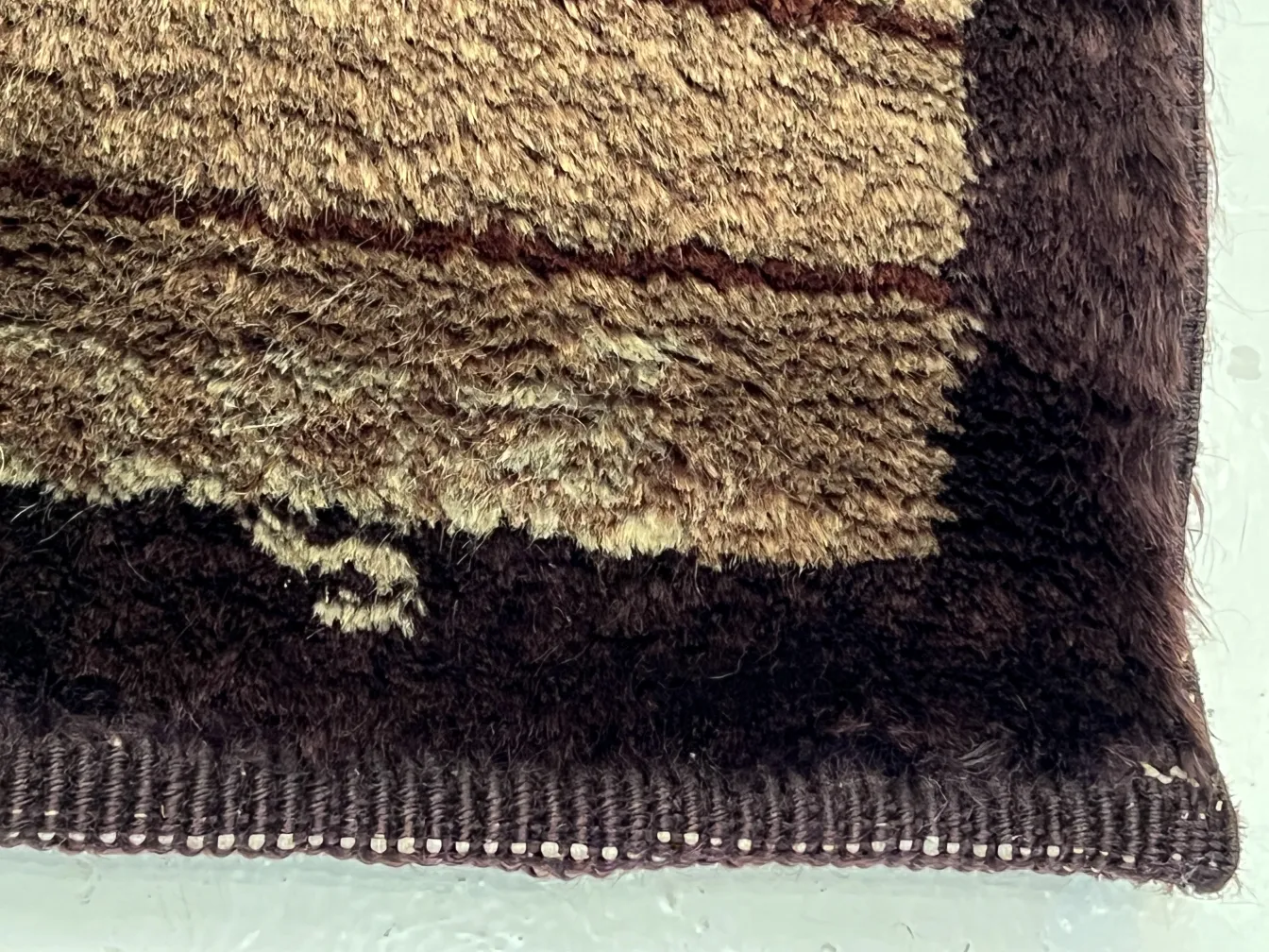 Tappeto antico con texture morbide in tonalità marrone e beige.