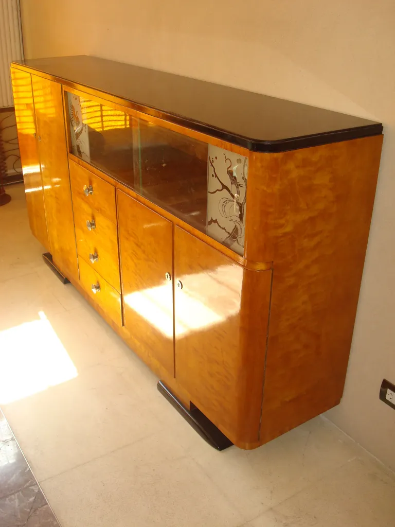 Antique bookcase with a shiny finish and decorative glass doors, light background.