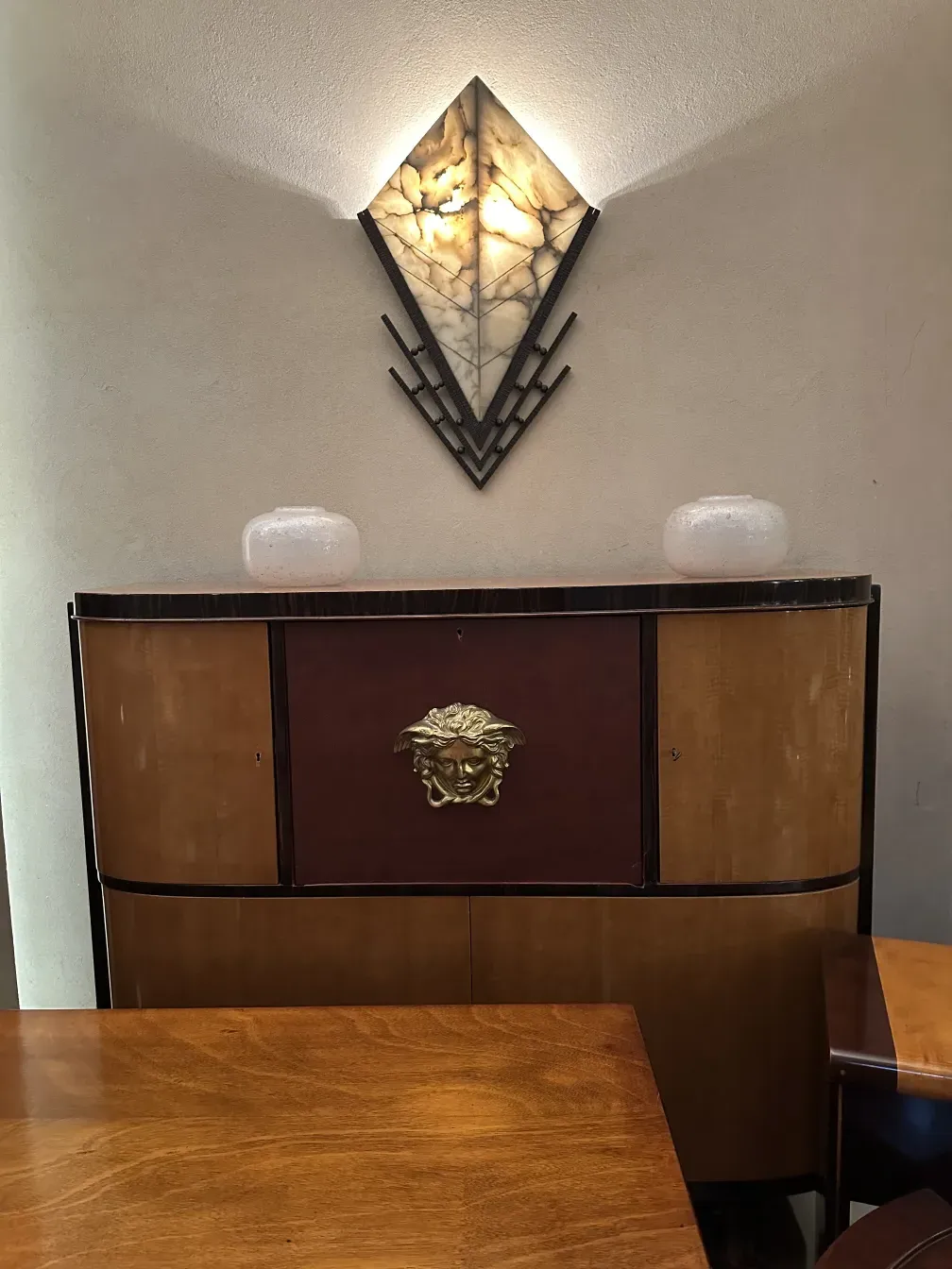 Antique bookcase with a unique design, adorned with a gold detail against a neutral background.