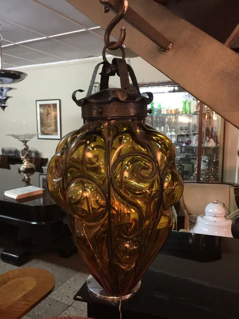 जटिल डिज़ाइन वाला प्राचीन पीला कांच का लालटेन एक आरामदायक सेटिंग में।