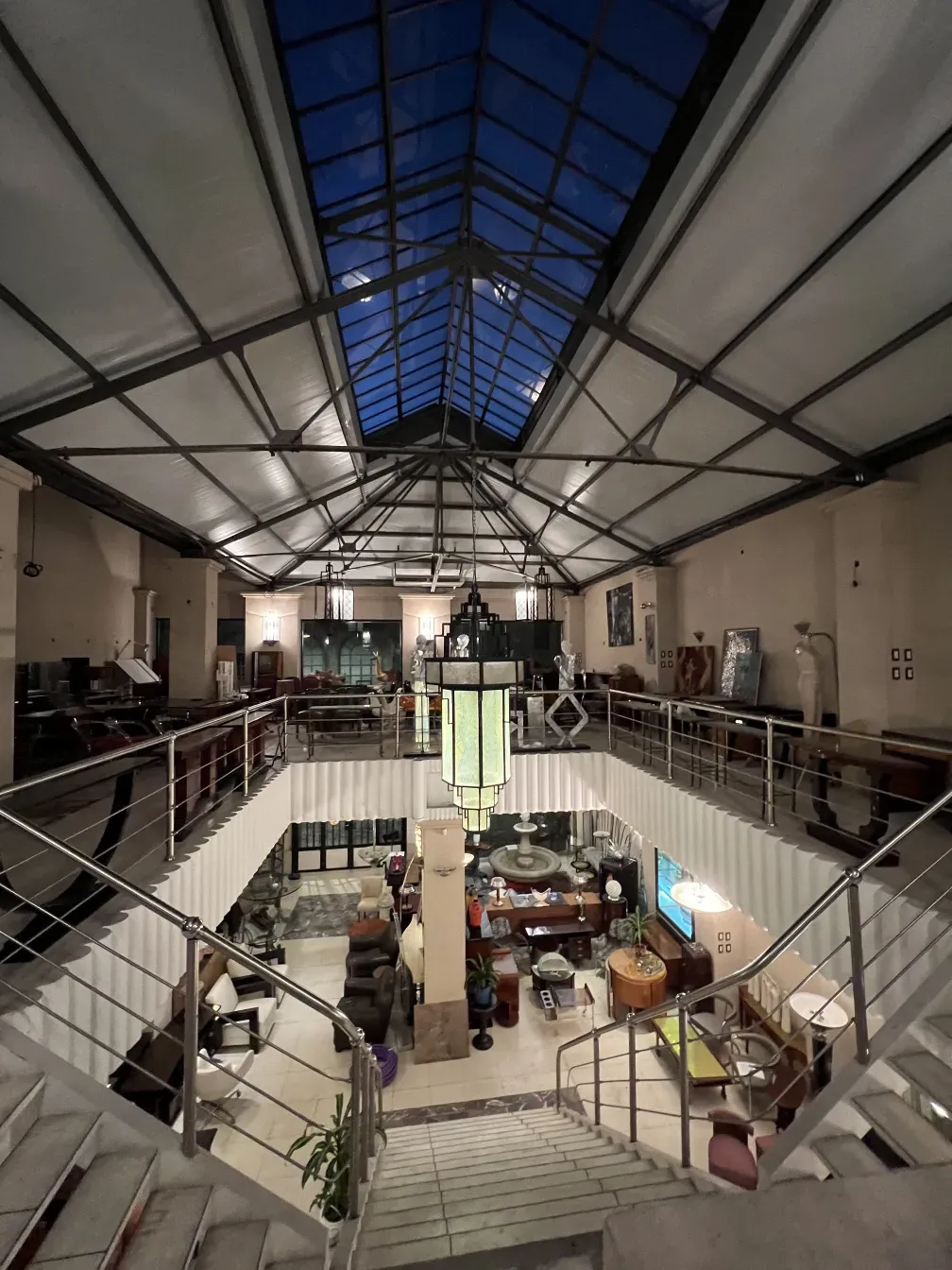 प्रकाशित स्थान में कांच का पुराना लालटेन, फर्नीचर और सजावट से घिरा हुआ।