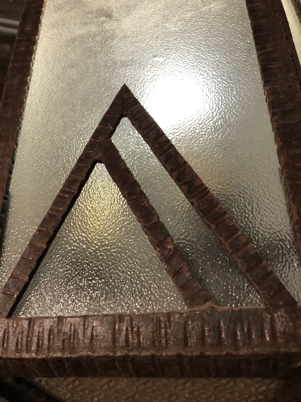 प्राचीन लालटेन, जिसमें बनावट वाला कांच और काला ढांचा है।