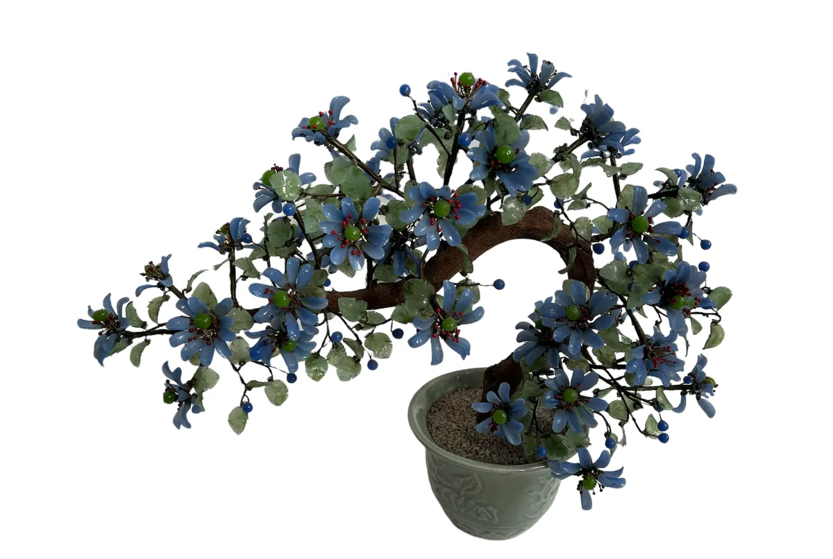 Antique bonsai decorated with blue flowers in pot.