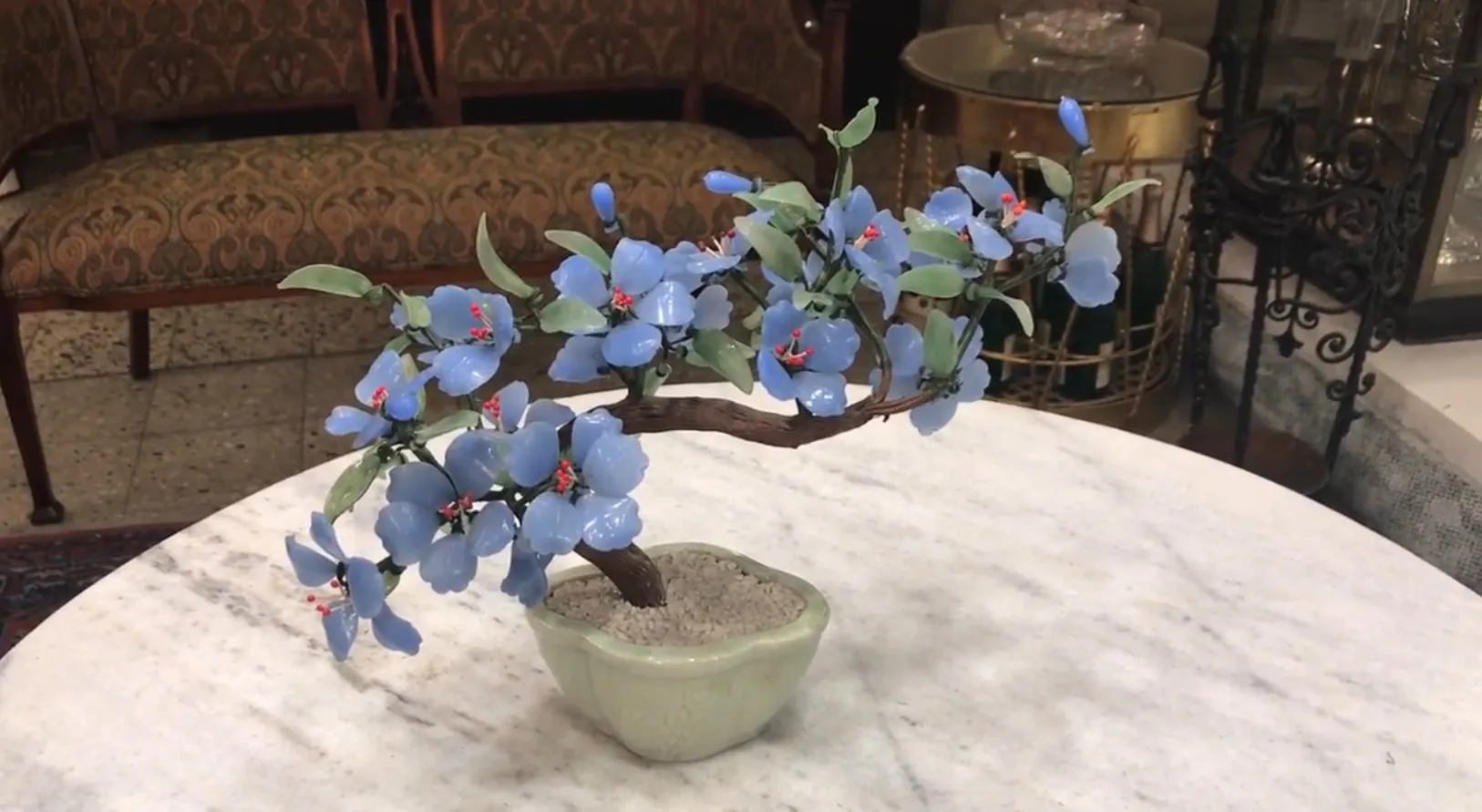 Beautiful antique bonsai with blue flowers in a green pot.