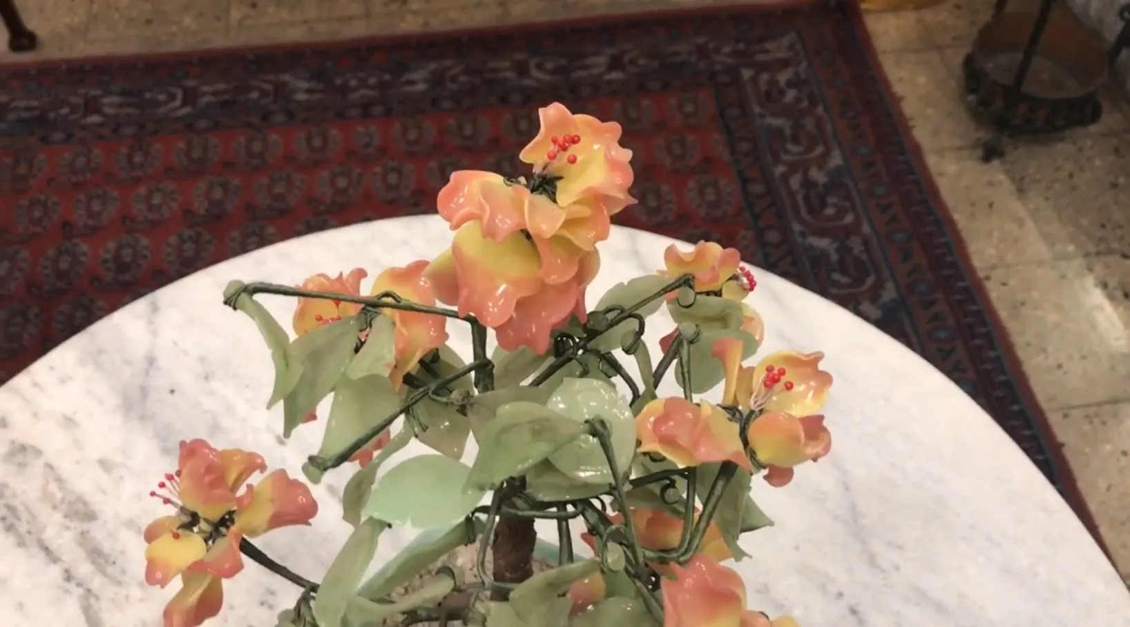 Antique bonsai with ceramic flowers and green leaves on table