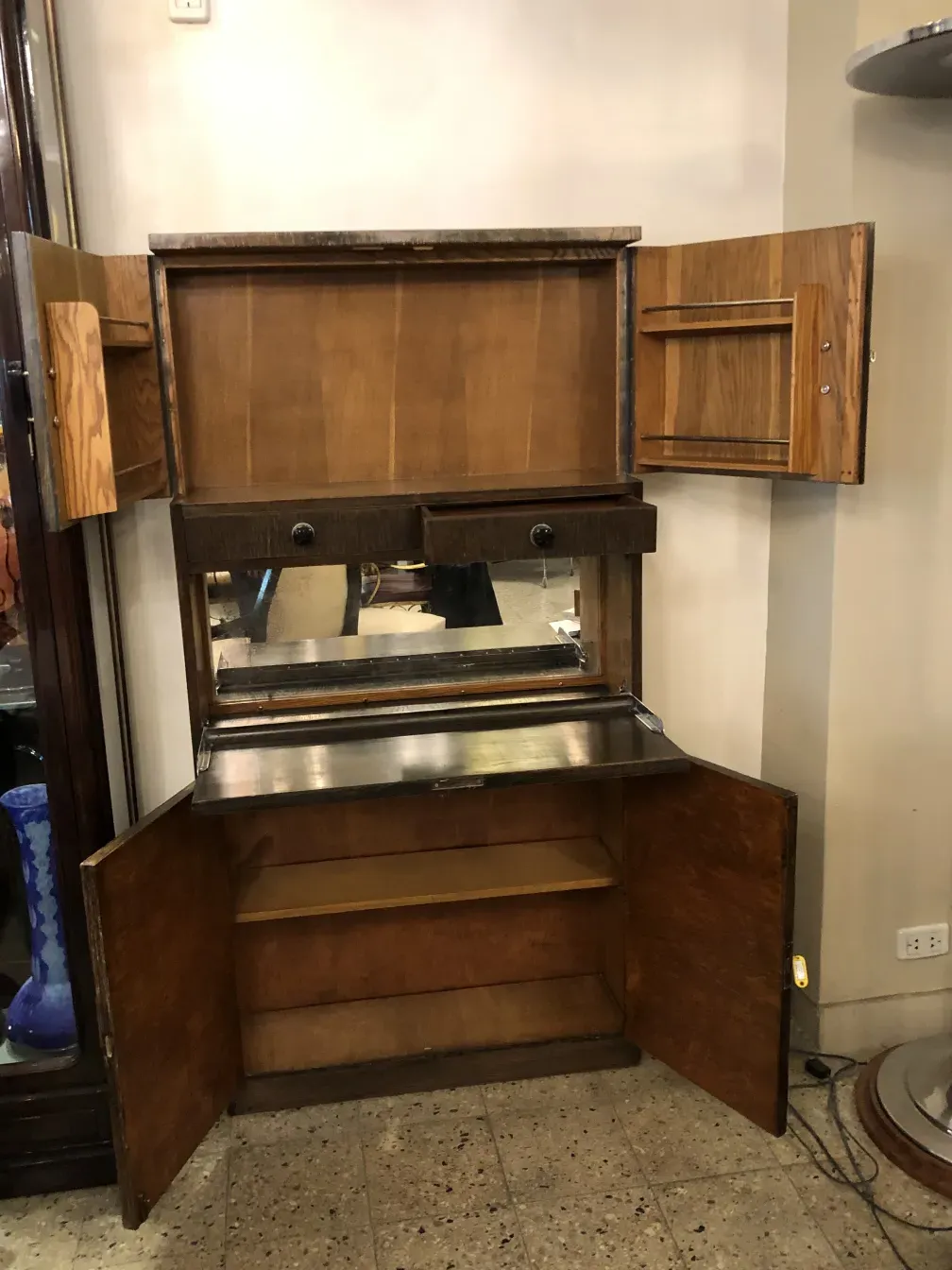 Antique bar cabinet with mirror and storage compartments.