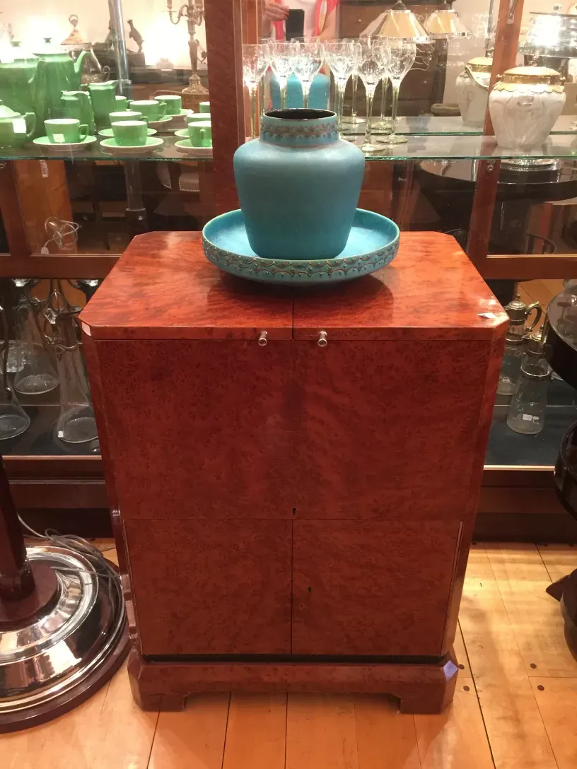 Antique bar cabinet with elegant decorations and a blue vase.