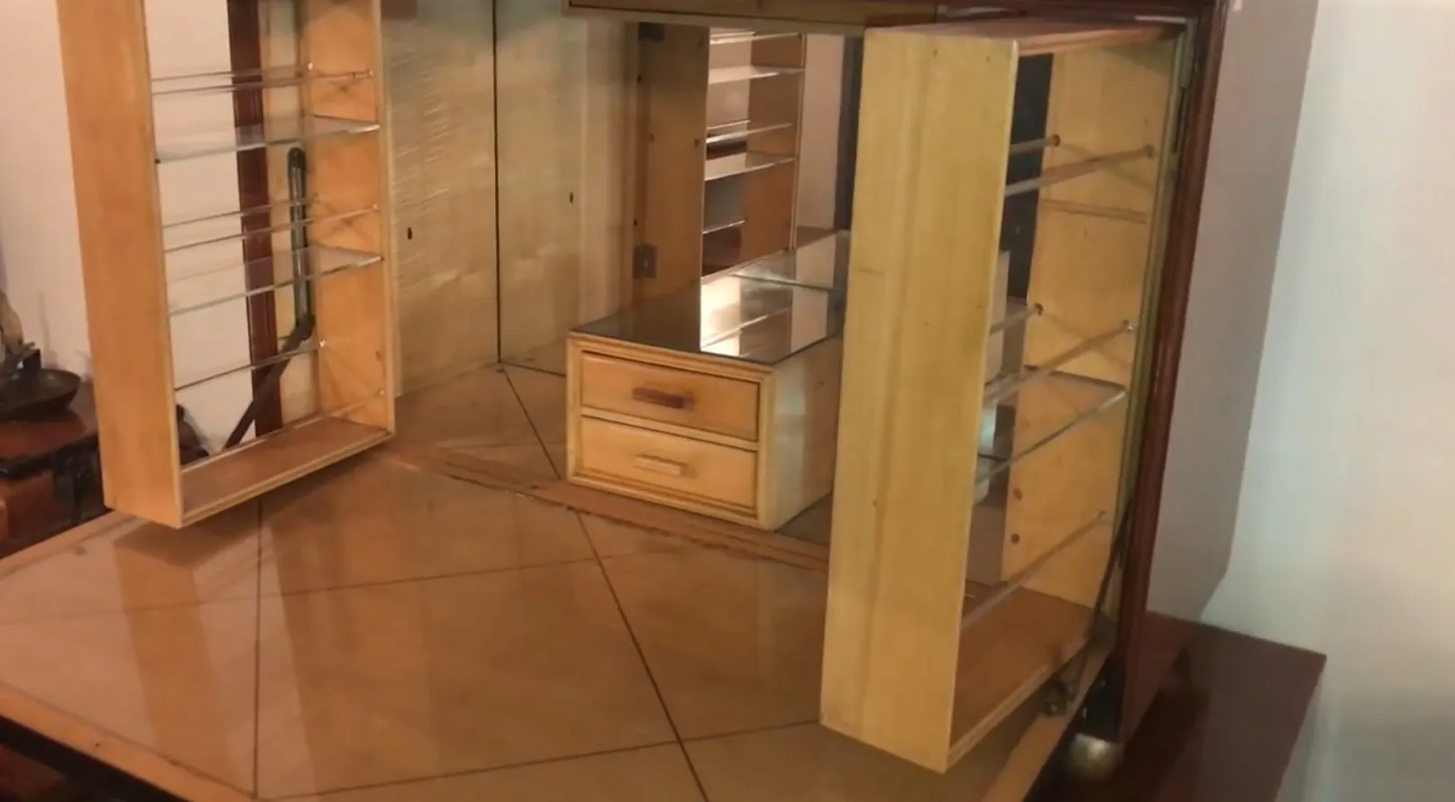Antique wooden bar cabinet with shelves and a drawer, set in a cozy vintage decor.