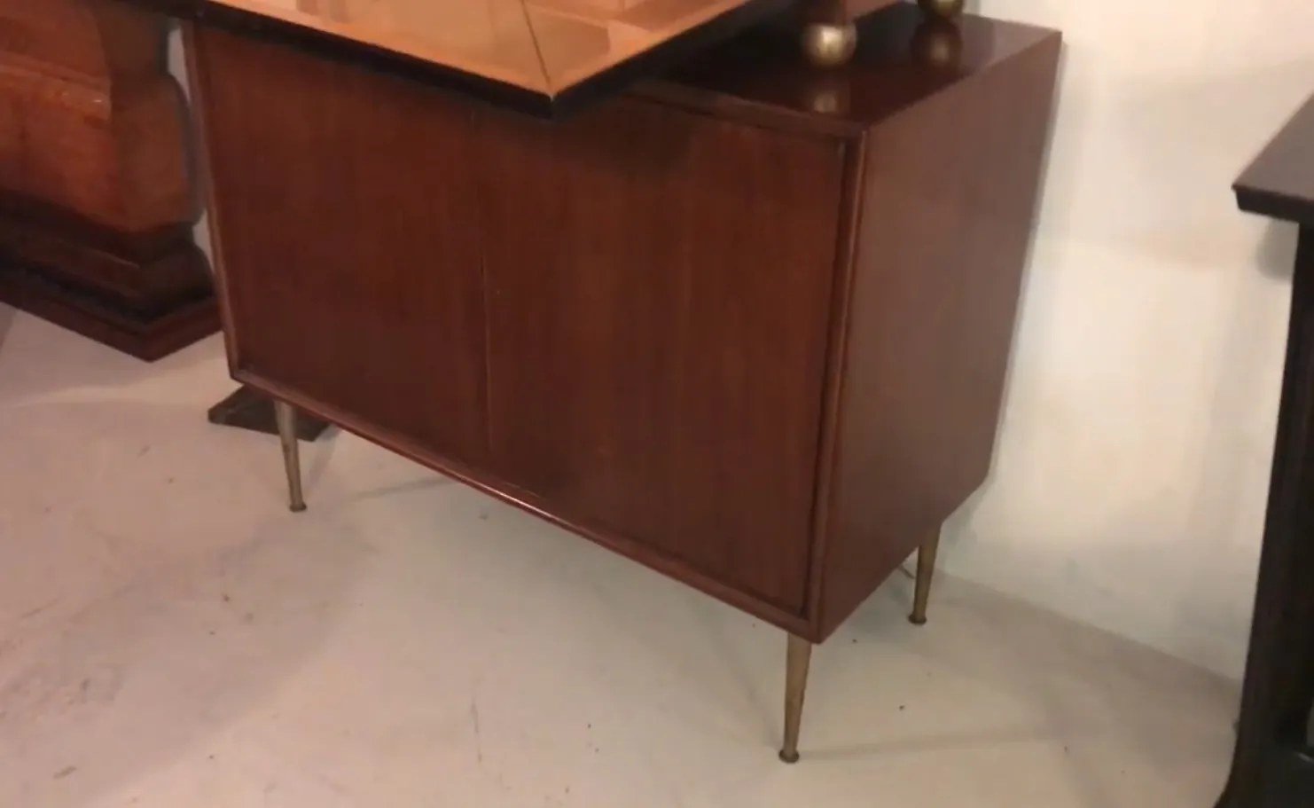 Antique bar cabinet in wood finish with golden legs.