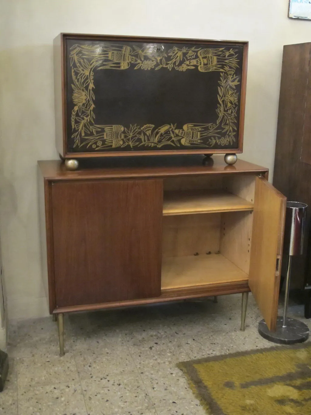 Antique bar cabinet with wood structure and golden floral designs.