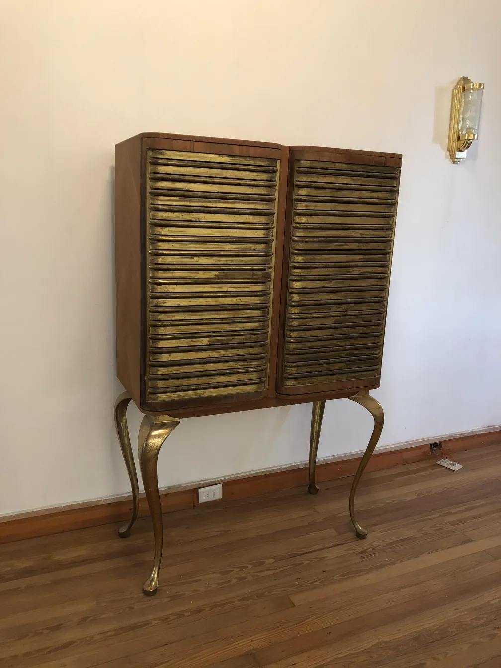 Antique bar cabinet with gold finishes and elegant design in a minimalist setting.