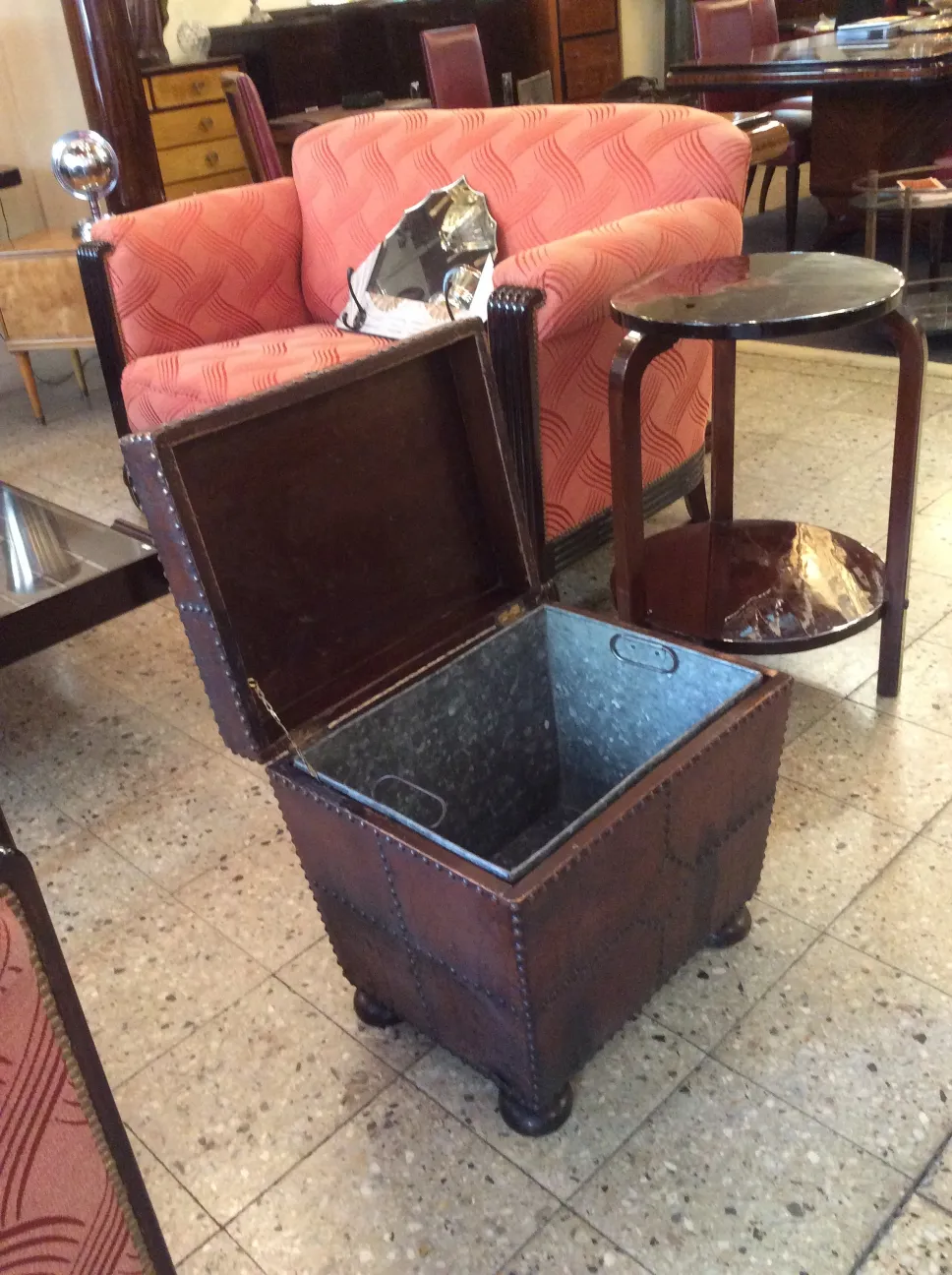 Antique bar container with metallic interior and red upholstery in living room setting.