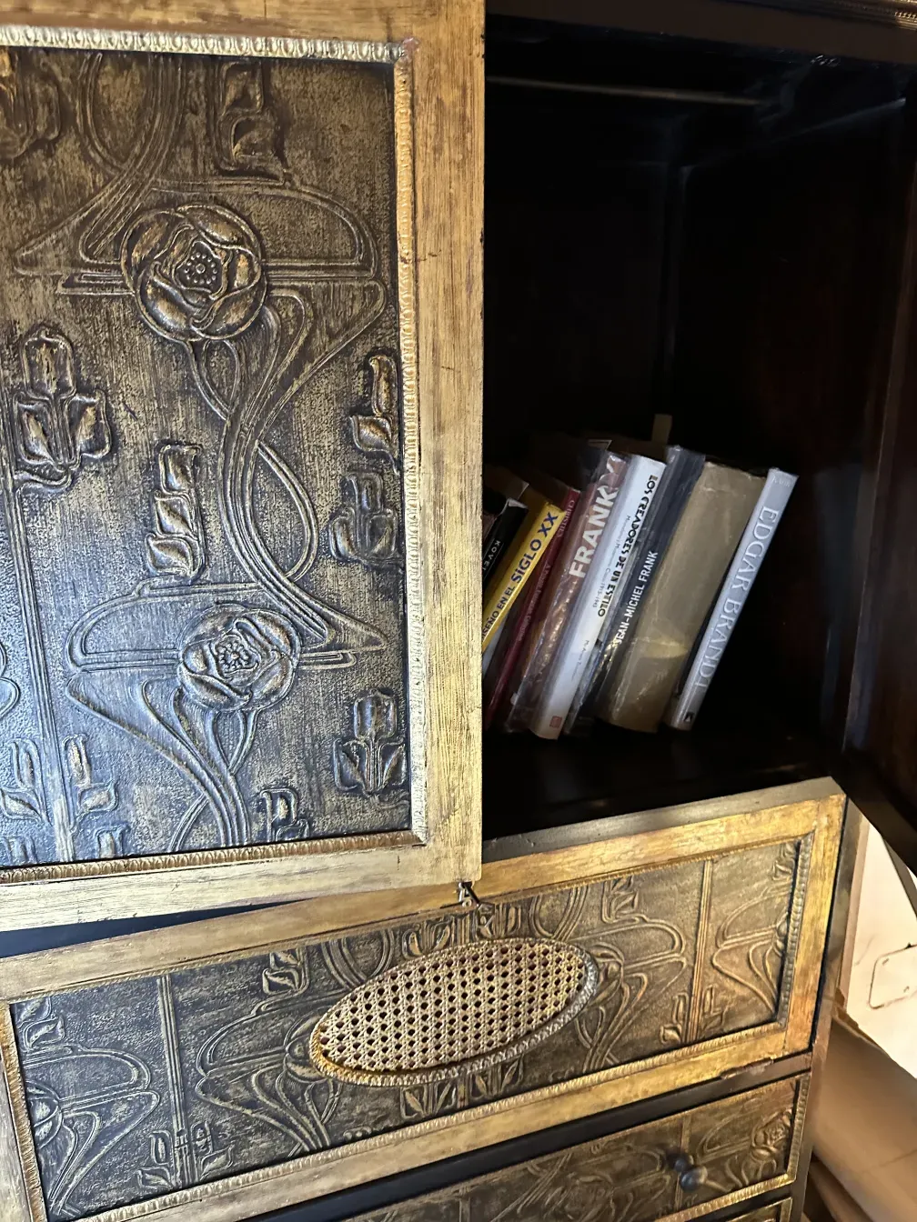 Antique bar with golden decor and books inside.