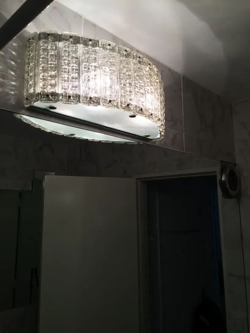Antique pair of glass sconces in lit bathroom