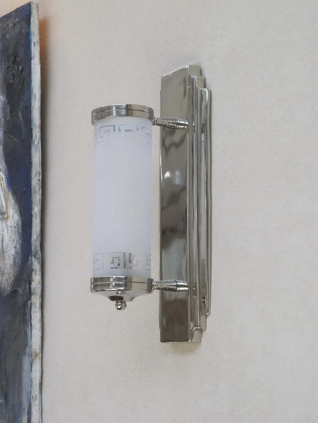 Pair of antique sconces with white shade and metallic frame, enhancing a soft wall with artwork